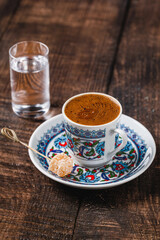 Turkish coffee in classic coffee cup with water and Turkish delight on wooden table
