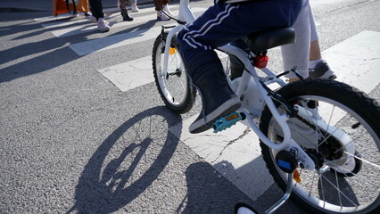 Naklejka premium Closeup child bicycle crossing city street on crosswalk. Kid crosses zebra lines outdoors in urban asphalt