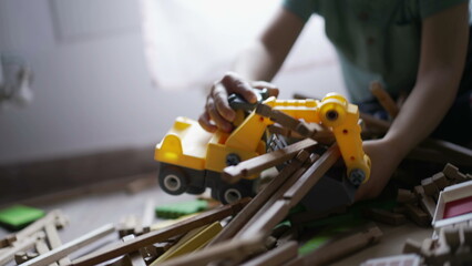 Child destroying wooden home toy with small bulldozer tractor. One little boy destroyer playing at home in playroom