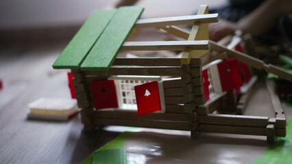 Child destroying wooden home toy with small bulldozer tractor. One little boy destroyer playing at...