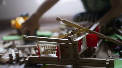 Child destroying wooden home toy with small bulldozer tractor. One little boy destroyer playing at home in playroom