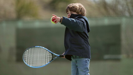One little boy holding tennis racket playing outside