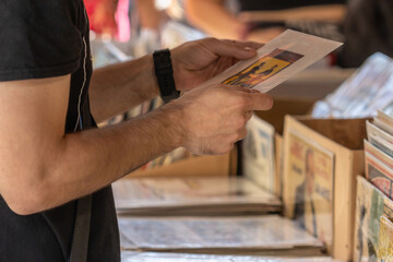 Selective focus on the right hand of an unrecognizable man at a flea market looking for vinyl records.
