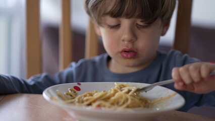 One little boy eating pasta with fork. Child eats lunch meal carb food. Kid nutrition concept