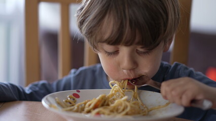 One little boy eating pasta with fork. Child eats lunch meal carb food. Kid nutrition concept