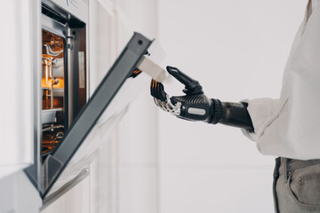 Female amputee is cooking using futuristic high technology bionic prosthesis. Daily routine.