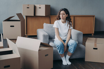 Hispanic woman feels hard to live alone. Young pretty lady is tired with boxes unpacking.