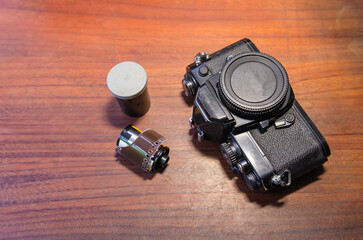 Film camera and 35 mm film roll on wooden table