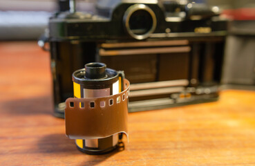 Film camera and 35 mm film roll on wooden table