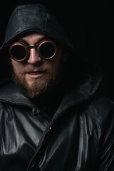 A man in a hood, wearing vintage steampunk goggles looking at the camera close-up