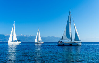 Fototapeta na wymiar sailing yacht boats with white sails in blue sea , seascape of beautiful ships in sea gulf with mountain coast on background