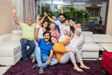 Portrait of Happy cheerful indian joint family sitting together at home. Asian senior and young...