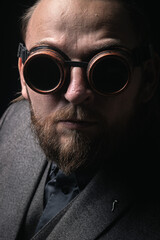 charismatic man in a classic suit and steampunk goggles on a black background stylish Portrait