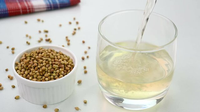 Serving coriander seed water in a glass cup.