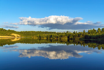 Fototapeta premium Snow - white clouds in the form of an airplane are reflected in the lake .