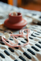 Coral and coconut beads  on pattern towel with clay pottery close up 