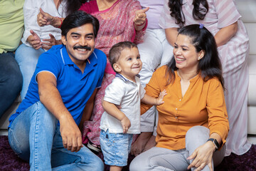 Portrait of happy young indian parents sitting with their little toddler child baby at home.