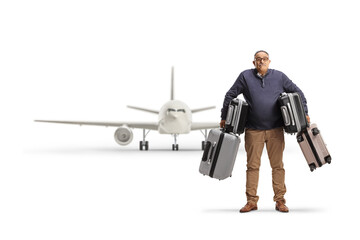 Confused mature man carrying heavy suitcases in front of an airplane