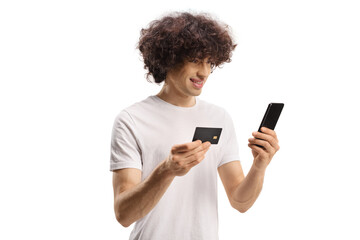 Casual young man with curly hair using a smartphone and a credit card