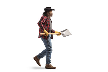 Full length profile shot of a farmer walking and holding a shovel