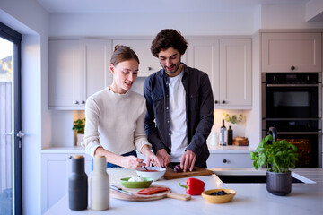 Couple In Kitchen At Home Making Homemade Pizza Together