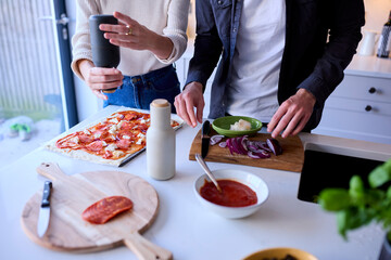 Close Up Of Couple In Kitchen At Home Making Homemade Pizza Together