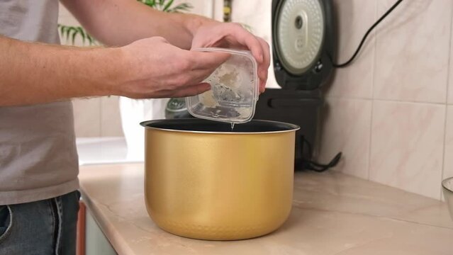 The man puts the frozen grated onion with juice into bowl of slow cooker. multicooker. Cooking lunch dinner for family at home. The process of cooking meat in French with potatoes, tomatoes, cheese.