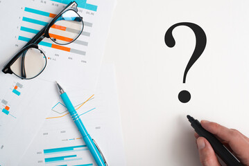 Business documents, financial reports with charts and infographics, hand drawn question mark with...
