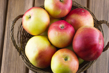 Top view of red apples in the basket on wooden background
