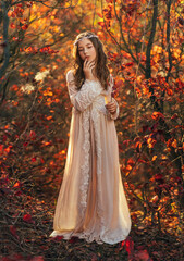 Obraz na płótnie Canvas Fantasy portrait teenage princess girl walking in forest, blond flowing hair cute face. White vintage dress, silver crown diadem on head. Autumn nature red orange leaves trees. Elf nymph young woman