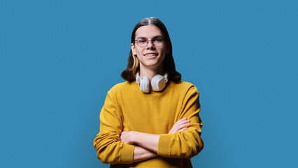 Confident young male posing with crossed arms against blue background