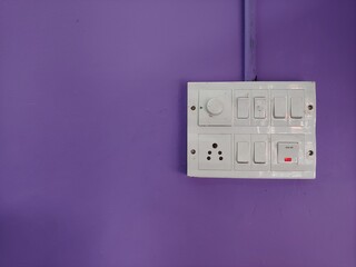 A white switch board on a violet wall