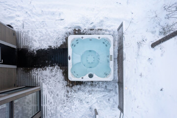 A modern outdoor hot tub embedded into the terrace on a cold winter's day. Aerial view from above.