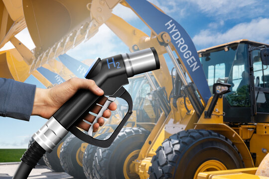 Hand with hydrogen fueling nozzle on a background of fuel cell construction machines. Concept	