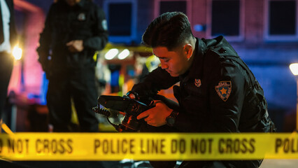Policeman Checking Camera after Taking Forensic Photos of Evidence Found on Crime Scene. Young...