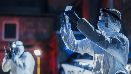 Forensics Team on Duty: Specialist Making Sure that Murder Weapon Found at Crime Scene is Properly Bagged in Evidence Bag. Experts Taking Photos of Clues and Traces Left by the Criminal