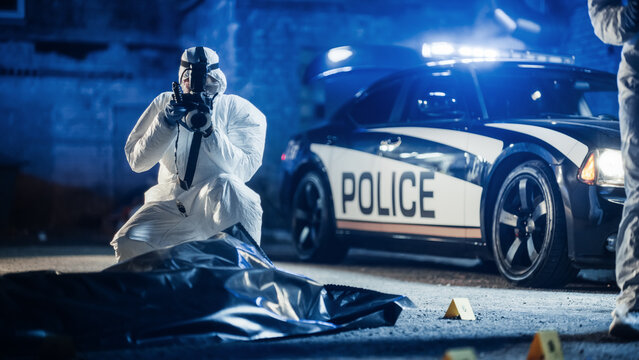 Forensics Expert Taking Photos of the Victim's Corpse in a Body Bag at a Crime Scene. Police Departmenet on Site, Gathering Clues and Recording Evidence to Open a Case File and Catch the Culprit