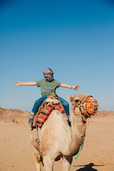 Little boy rides a camel and enjoys his vacation in Africa. Great experiences for children during the holidays