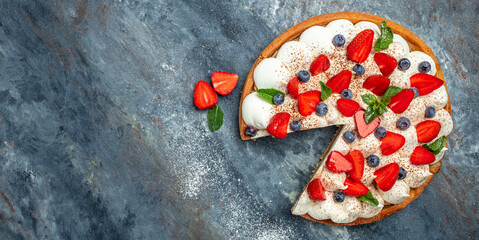 Homemade tart pie or cake with whipped cream and fresh strawberries, raspberries, blueberry on gray background. banner, menu, recipe place for text, top view