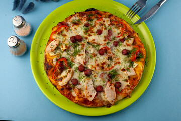 Pizza with meat, bacon, sausages, sausage, parmesan and dill, cheese, sauce. Food in a plate on a blue background. Menu. Homemade pastries. Meal with meat. Food on the table.