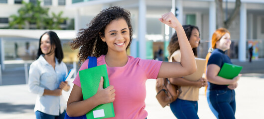 Successful cheering hispanic female student with group of young adults