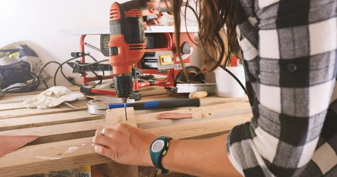 Carpenter female drilling holes in wood, close up 4k video