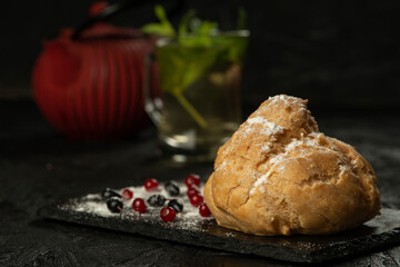 Freshly baked big eclair on a black cutting board