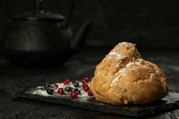 Freshly baked big eclair on a black cutting board