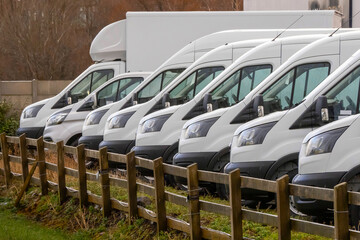 Row of white commercial vans in a dealership for sale or rent. Used and new busses. Transport...