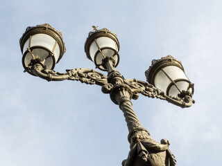 Fototapeta na wymiar Old style metal lamp against light blue sky. Old vintage design.