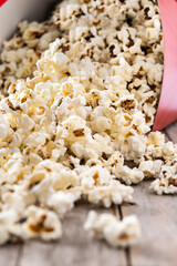Salted popcorn scattered on wooden table. Close up