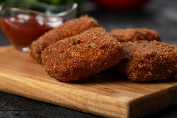 chicken nuggets and sauce on a board .