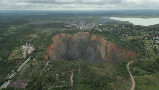 Rising aerial peers down into big hole open pit of diamond mine in ZA