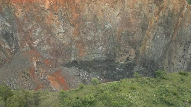 Aerial tilt looks over rim into big hole at Cullinan Diamond Mine, ZA